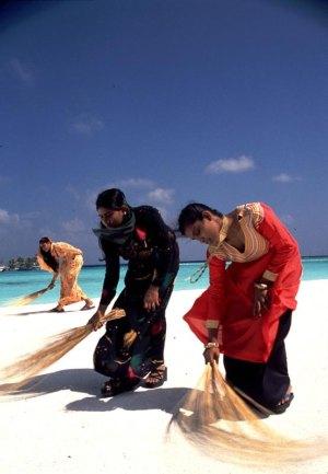 Women sweeping beach Maldives